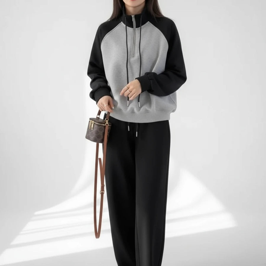 Person wearing a black and gray hoodie with a handbag indoors