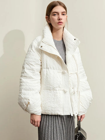 Person wearing a white quilted jacket against a plain background