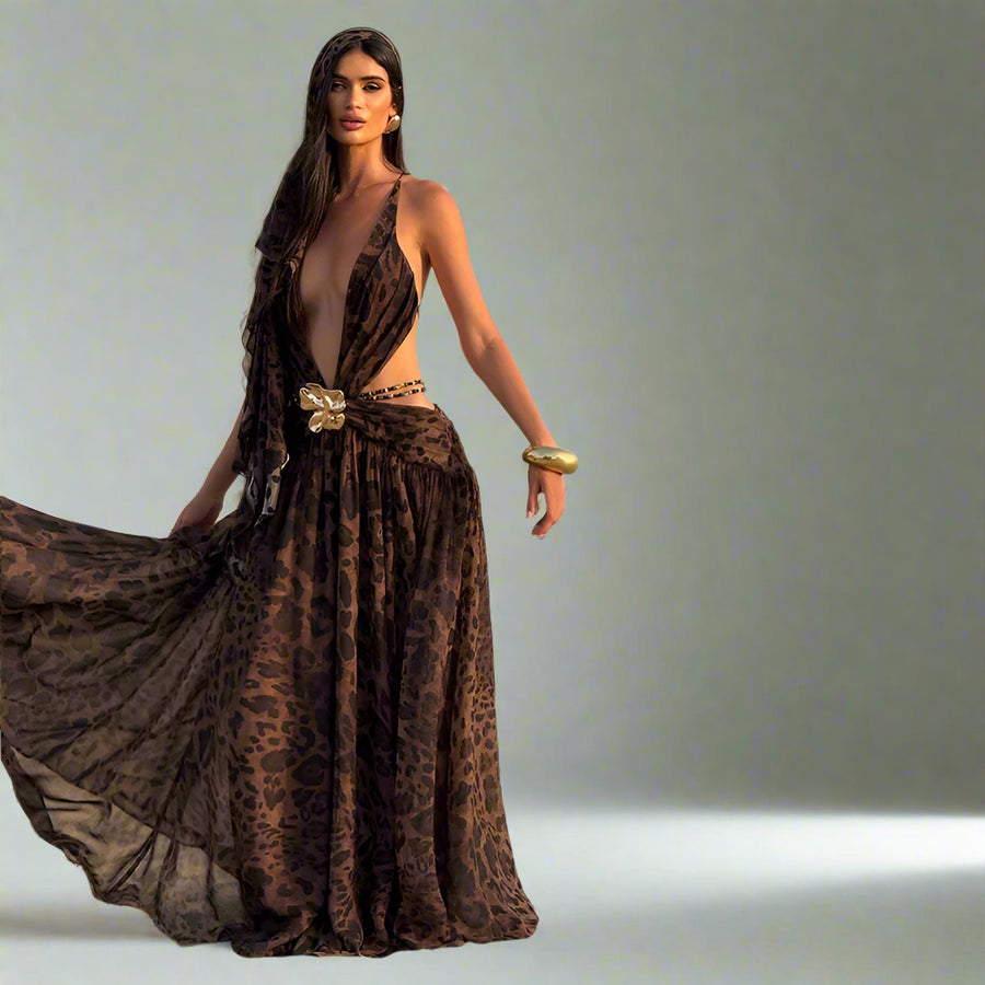 Woman in a leopard print dress walking in a desert with camels in the background