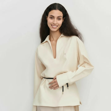 Woman wearing a cream-colored outfit against a plain background