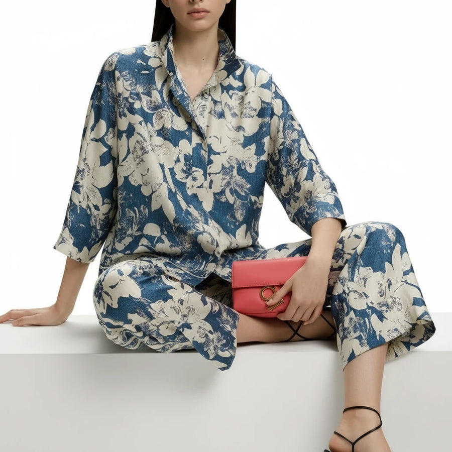 Woman wearing a floral jumpsuit holding a red clutch on a white background