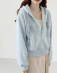 Light blue hoodie worn by a person with a neutral background