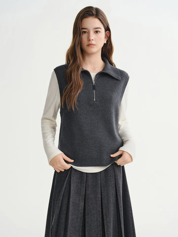 Woman wearing a dark gray vest over a white shirt on a white background