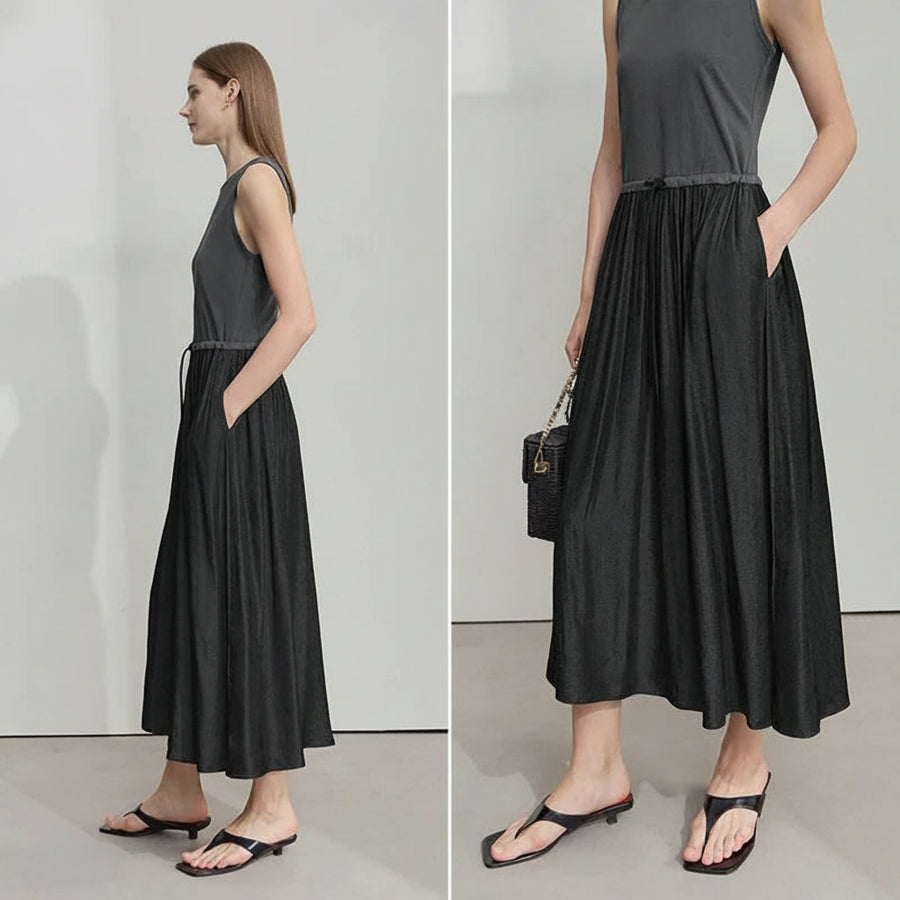 Woman wearing a black dress with a gray top, standing against a plain background.