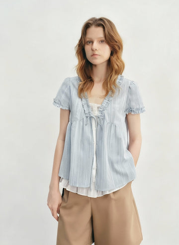 Woman wearing a light blue striped blouse with a white shirt underneath on a gray background, branded 'DUSHU'.