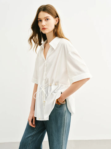 Woman wearing a white blouse and blue jeans on a plain background