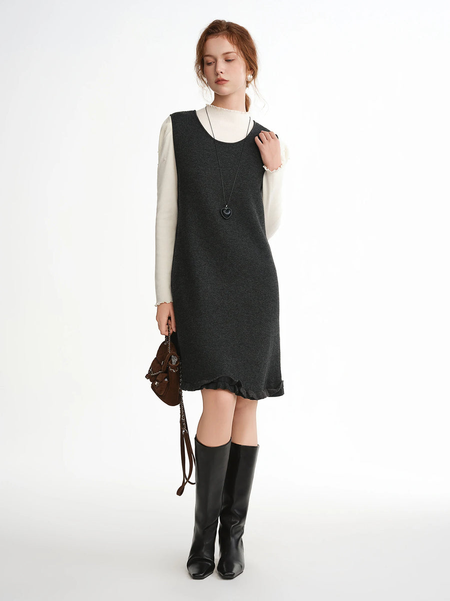 Woman wearing a black dress over a white shirt with black boots on a white background