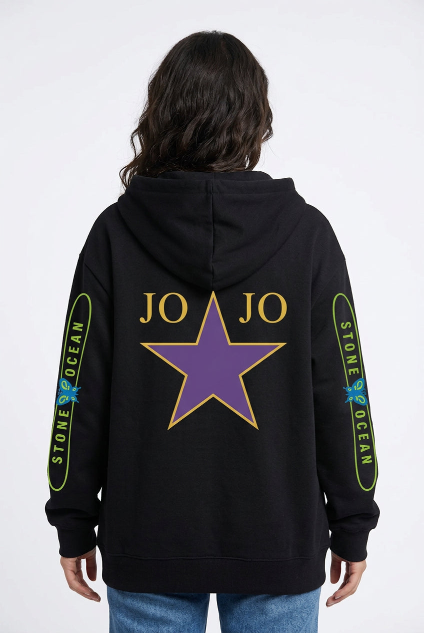 A person standing outdoors on a sports field wearing an oversized black hoodie from the back. The hoodie has a large purple star outlined in yellow on the back, with 'JO JO' text and smaller text with flowers on both sleeves.