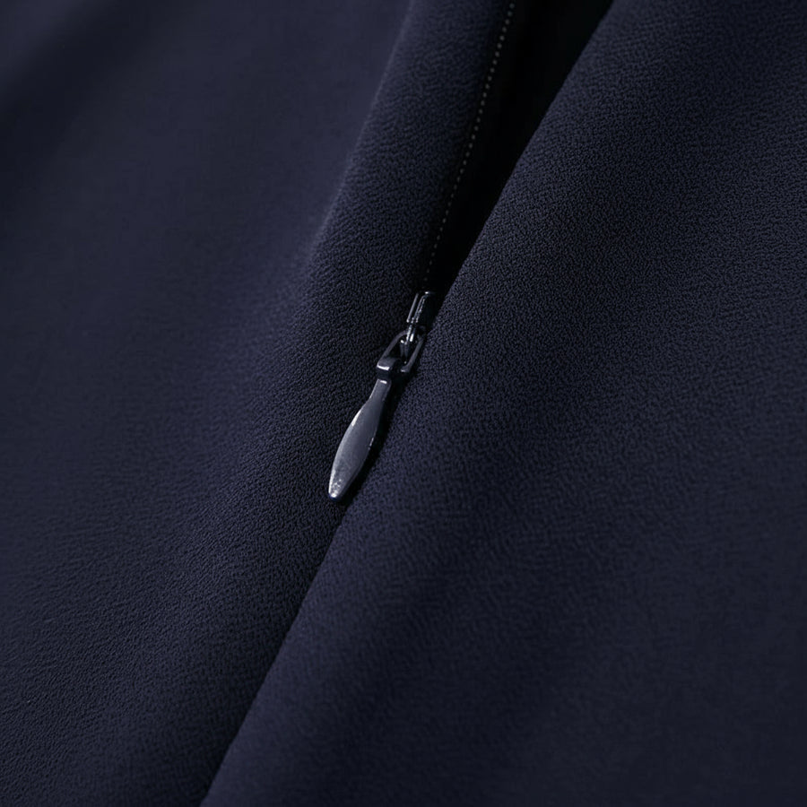 Close-up of a zipper on a dark fabric with Amii logo.