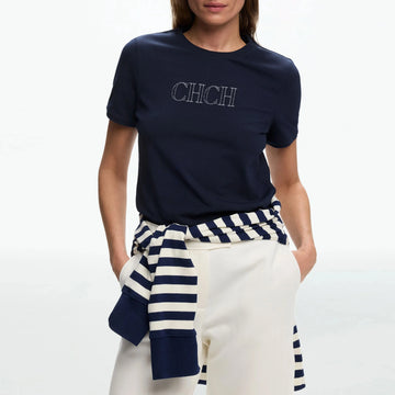 Person wearing a navy blue t-shirt with 'CHCH' text, white pants, and a navy and white striped top.