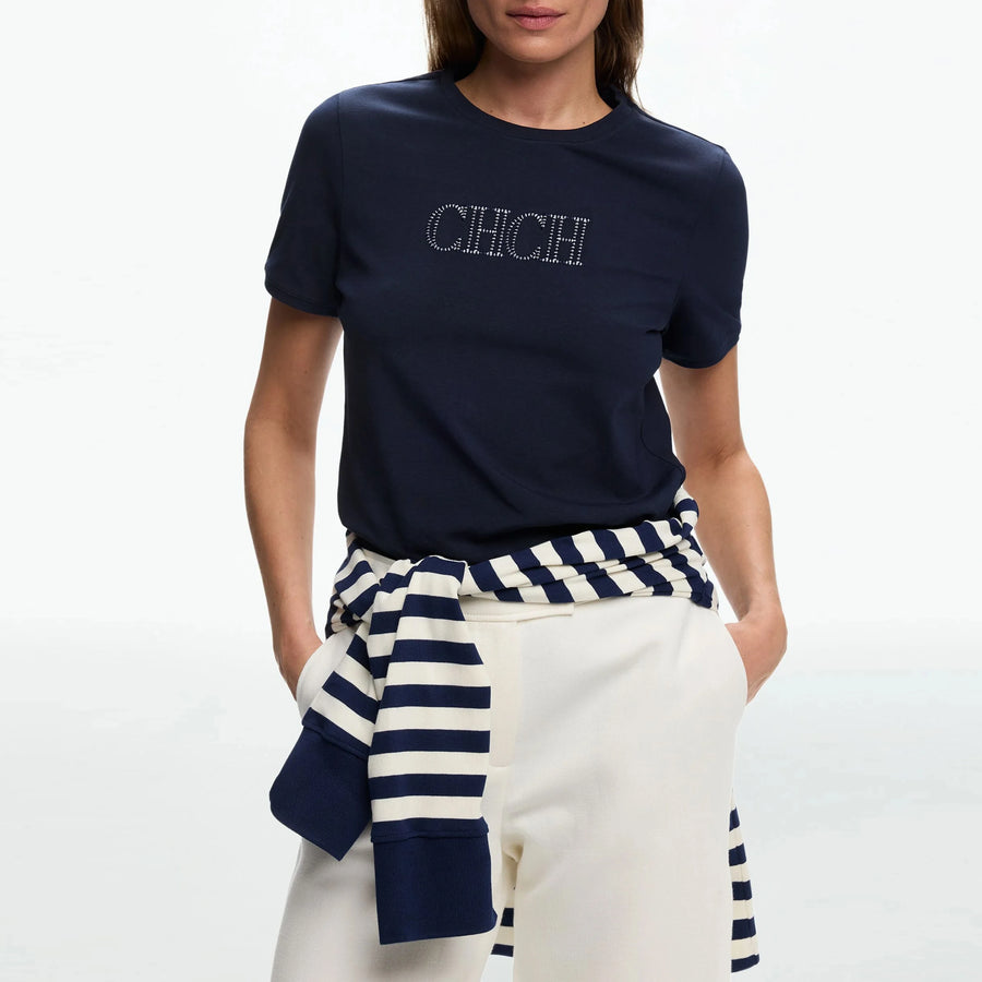 Person wearing a navy blue t-shirt with 'CHCH' text, white pants, and a navy and white striped top.