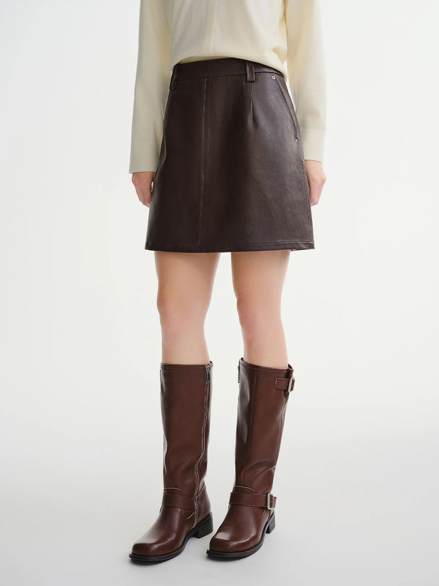 Person wearing a brown leather skirt and boots on a white background