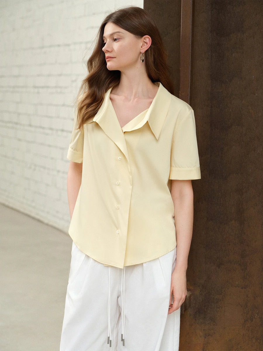 Woman wearing a light yellow blouse and white pants against a neutral background