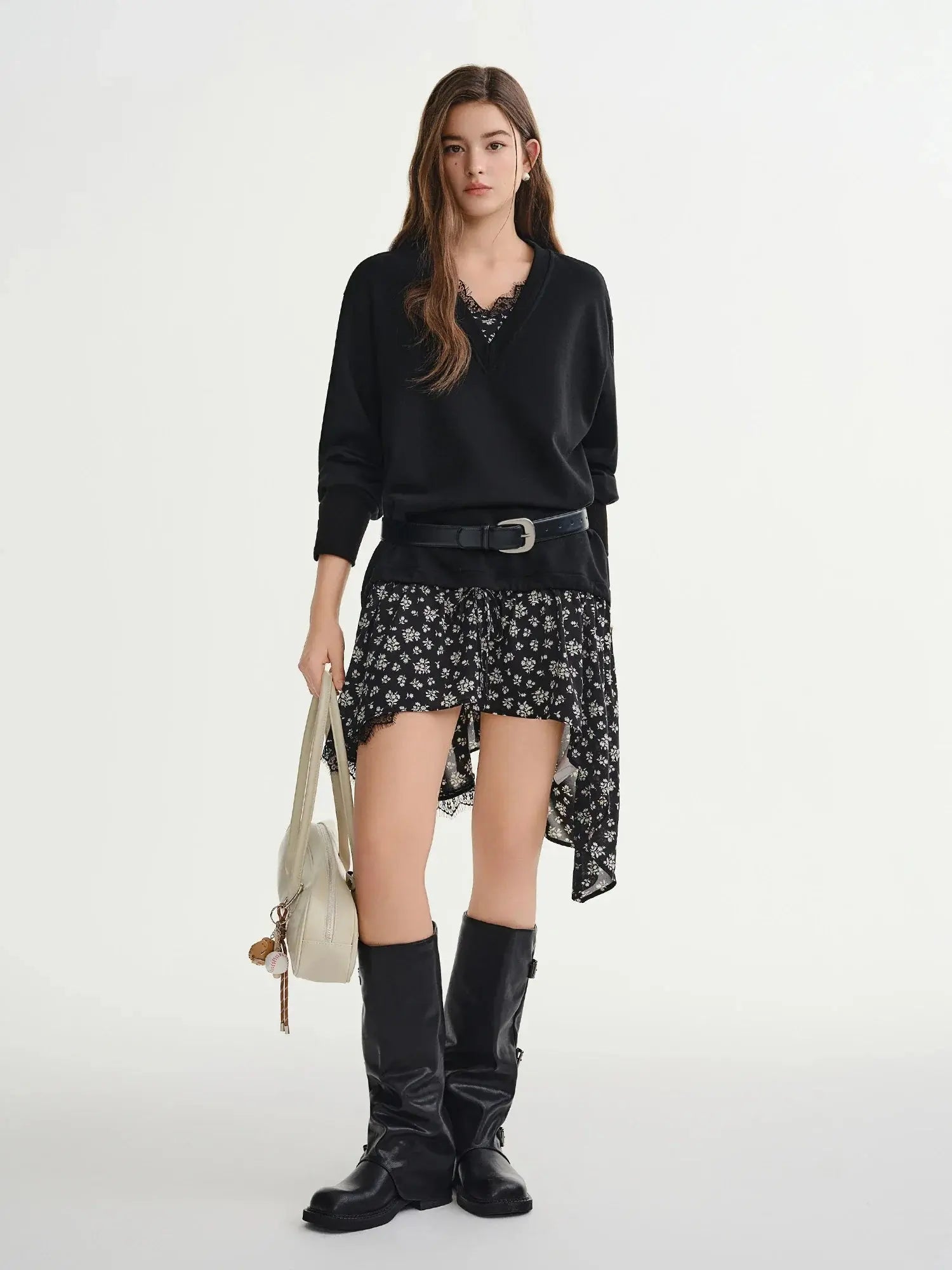 Woman wearing a black sweater, floral skirt, and black boots on a white background