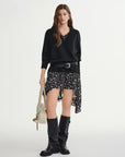 Woman wearing a black sweater, floral skirt, and knee-high boots on a white background