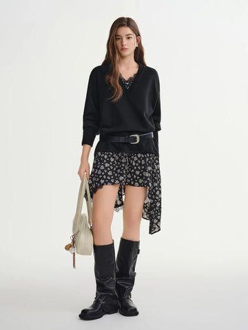 Woman wearing a black sweater, floral skirt, and knee-high boots on a white background