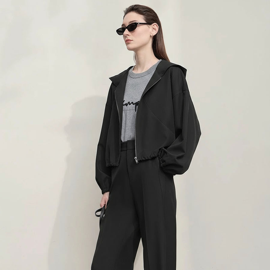 Woman wearing a black outfit with a gray shirt underneath, standing against a plain background. Brand 'AMII' visible.