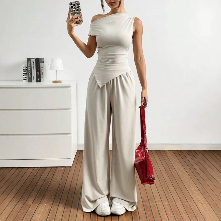 Person wearing a white outfit holding a red bag in a minimalistic room.