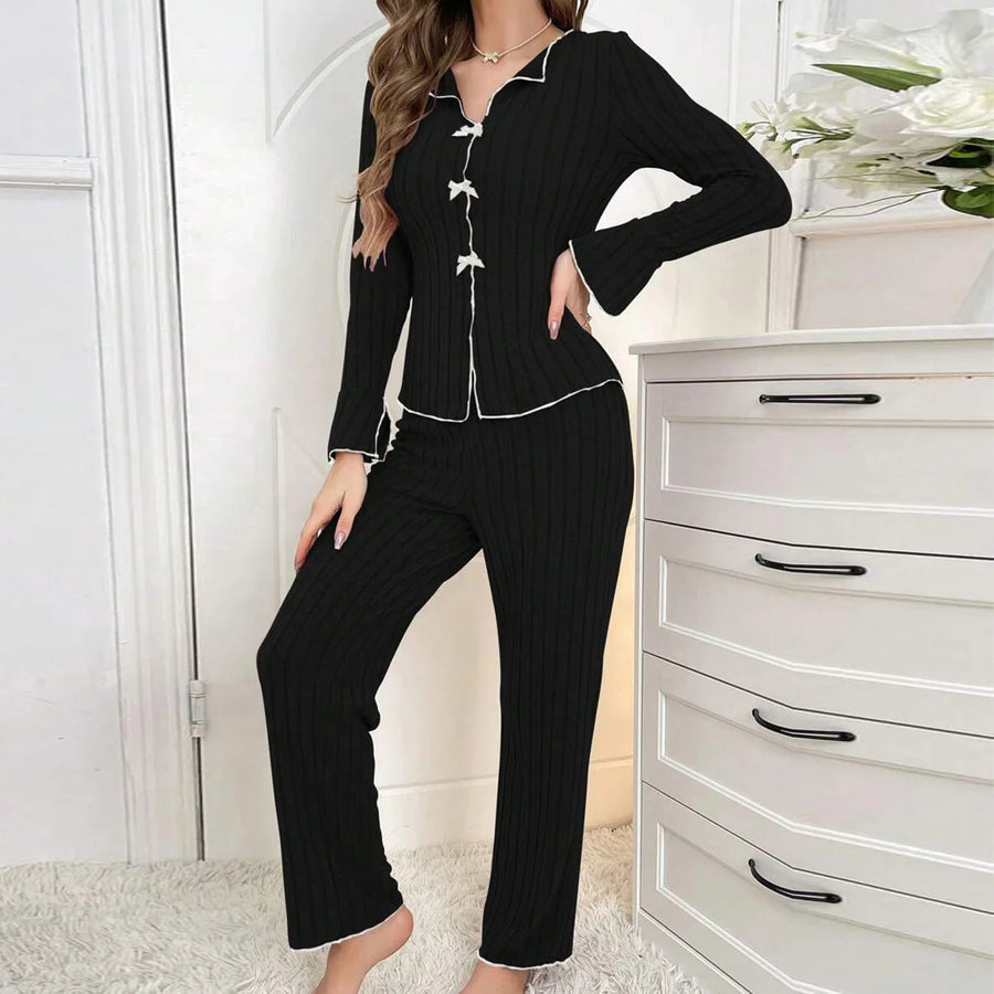 Woman wearing a black ribbed pajama set in a bedroom setting.