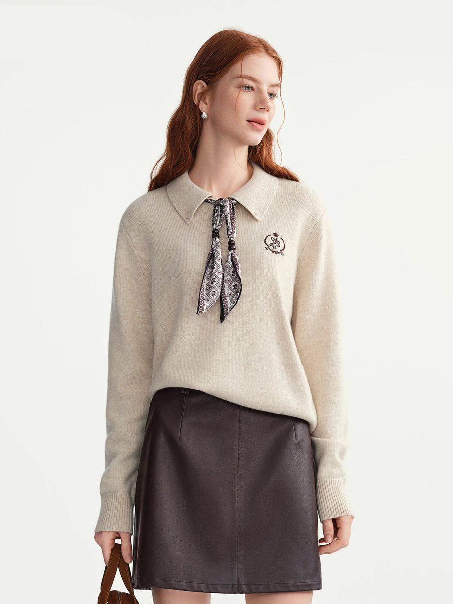 Woman wearing a beige sweater with a patterned tie and a brown leather skirt on a white background, with 'DUSHU' branding.