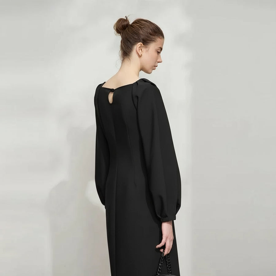 Woman wearing a black dress with a subtle pattern on a light gray background