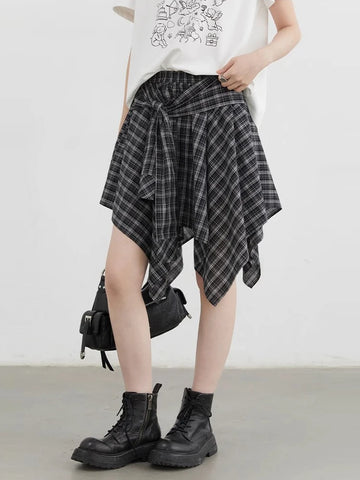 Person wearing a plaid skirt and black boots on a plain background