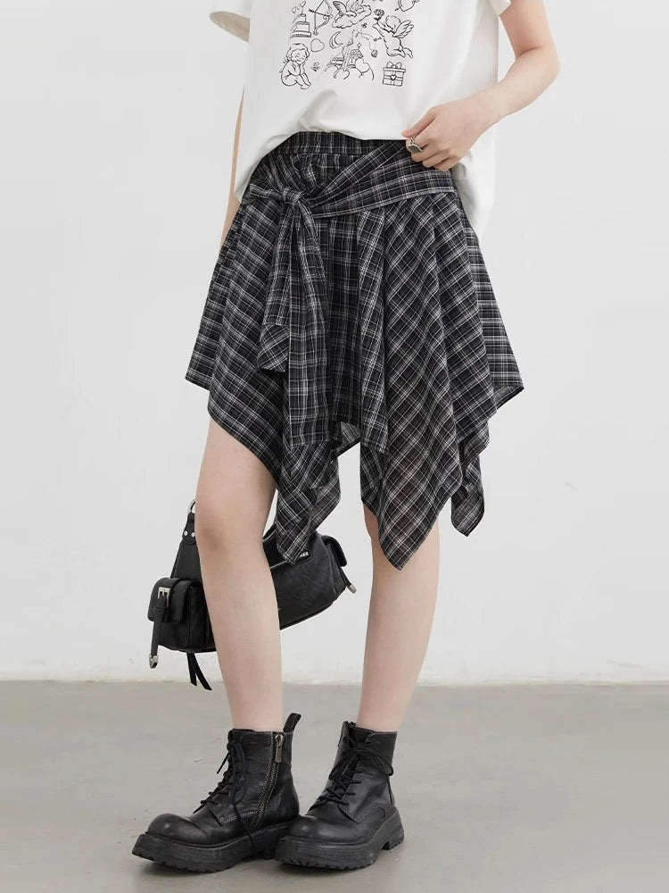 Person wearing a plaid skirt and black boots on a plain background