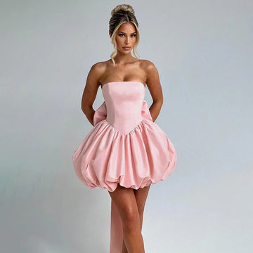 Woman wearing a pink strapless dress against a gray background
