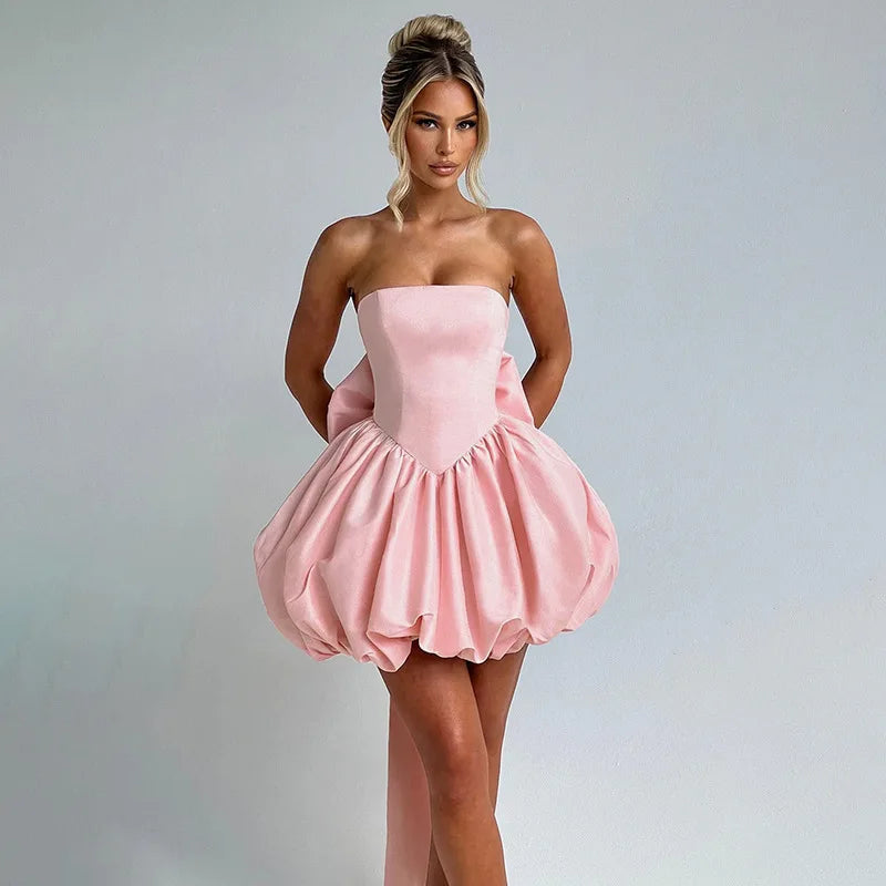 Woman wearing a pink strapless dress against a gray background