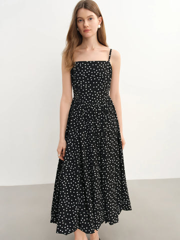 Woman wearing a black polka dot dress against a white background