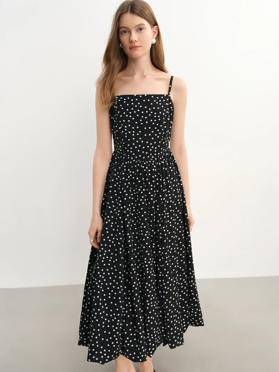 Woman wearing a black polka dot dress against a white background