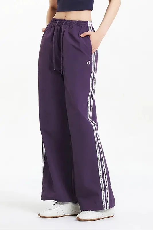 Purple pants with white stripes worn by a person on a white background.