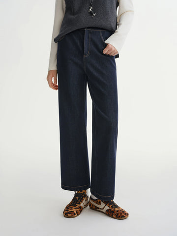 Person wearing dark blue jeans with a plain background