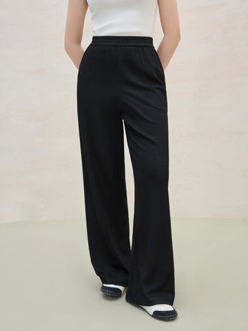 Person wearing black wide-leg pants on a plain background