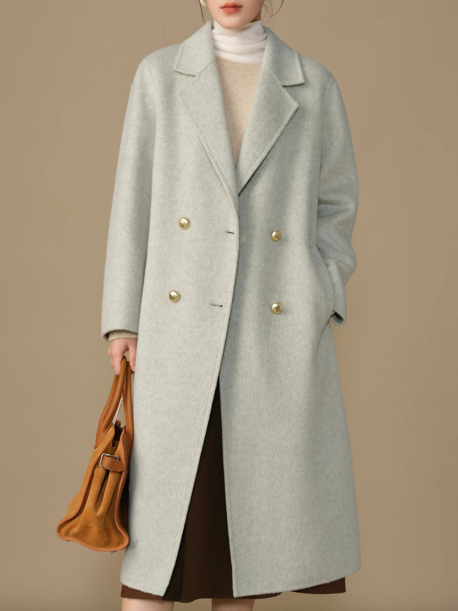 Person wearing a gray coat with gold buttons on a beige background