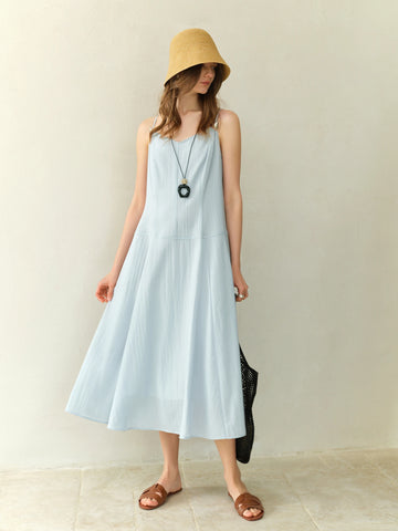 Woman wearing a light blue dress and yellow hat indoors