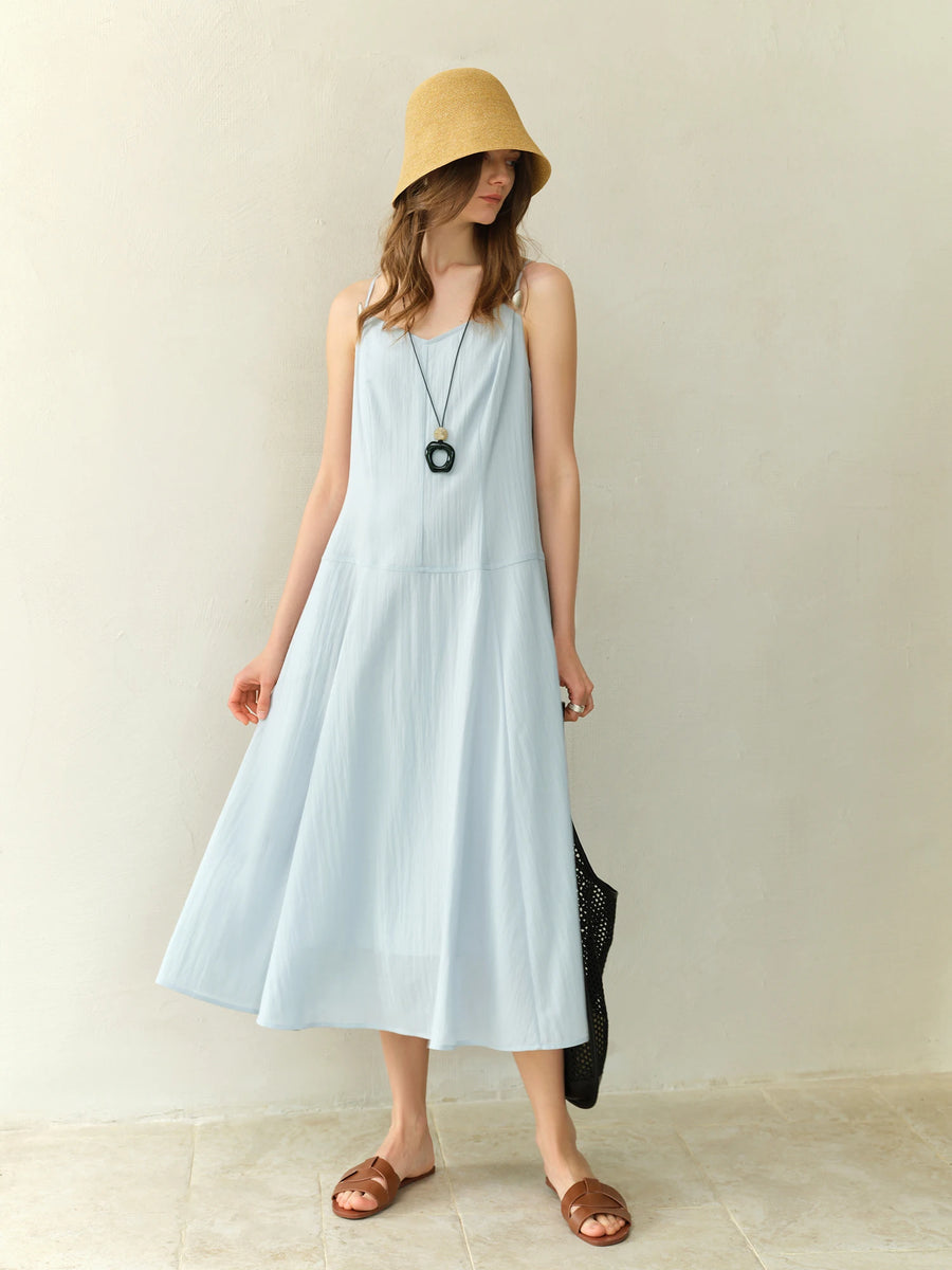 Woman wearing a light blue dress and yellow hat indoors