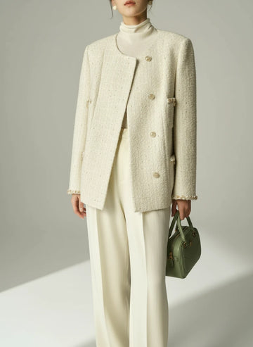 Person wearing a light-colored textured coat over a white outfit on a neutral background