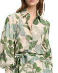 Woman wearing a floral patterned blouse with green and blue leaves on a white background