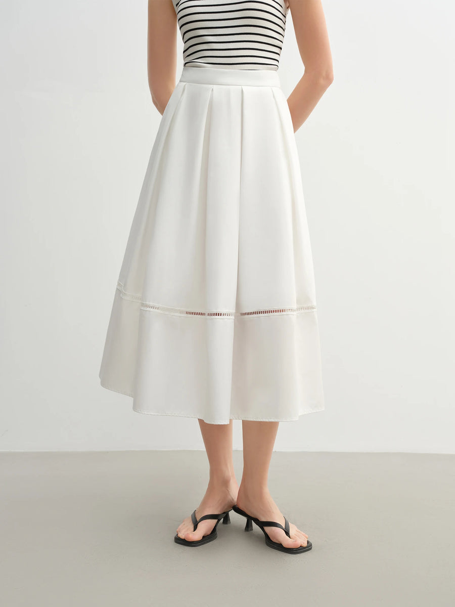 Person wearing a white skirt and black and white striped top on a plain background