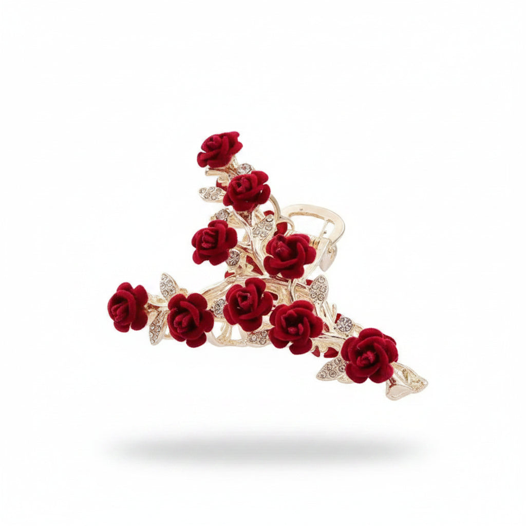 Decorative hair clip with red roses and gold accents held by a hand against a beige background