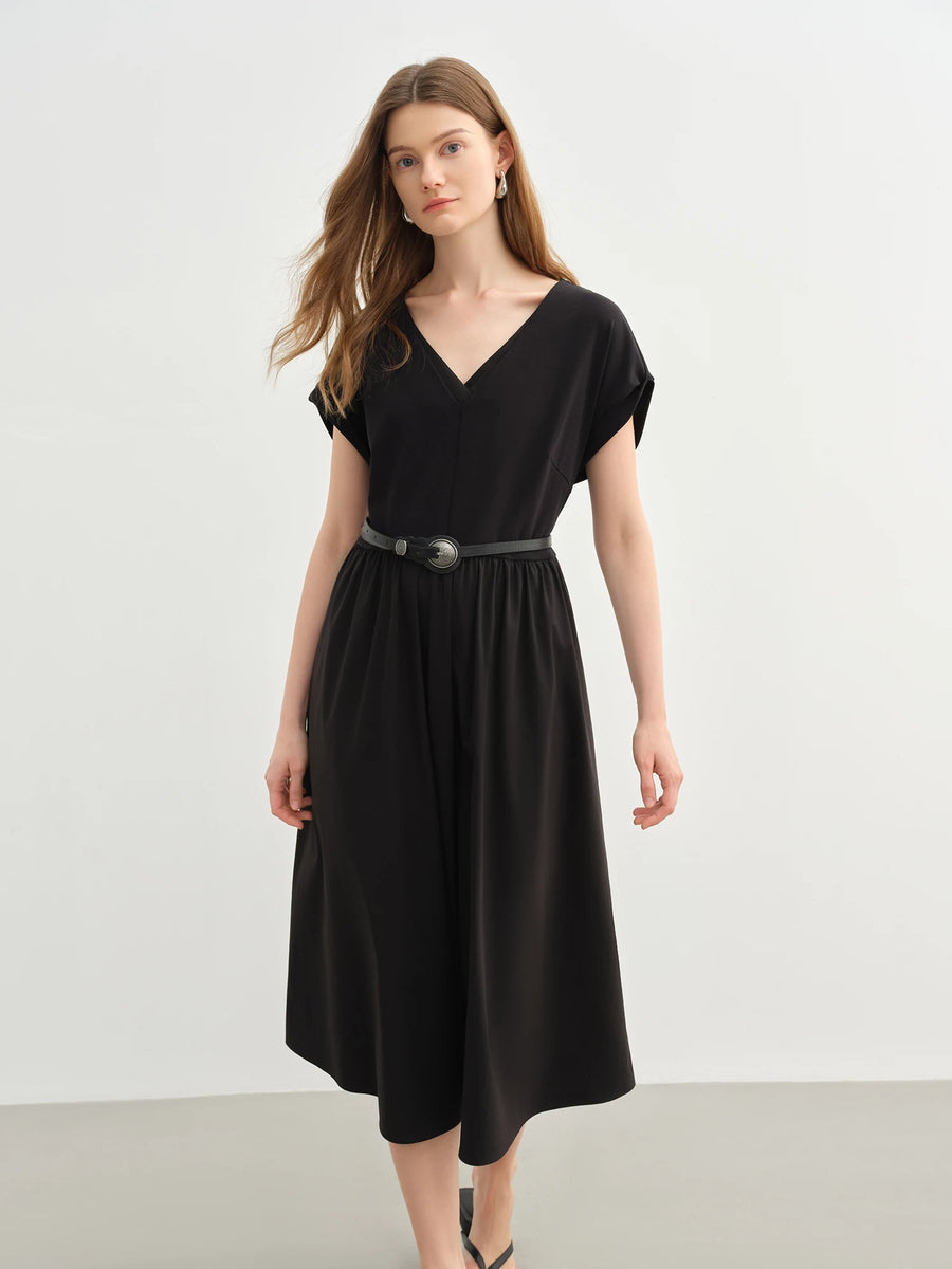 Woman wearing a black dress with a belt against a white background