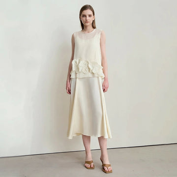 Woman wearing a white dress with floral details by Amii on a plain background