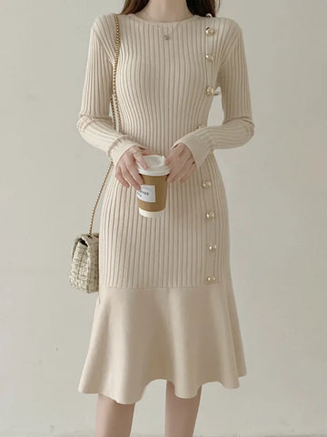 Woman wearing a beige ribbed dress holding a coffee cup against a plain background