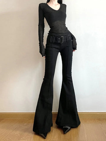 Person wearing a black outfit with bell-bottom pants on a plain background
