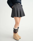 Person wearing a dark gray pleated skirt with colorful socks on a white background