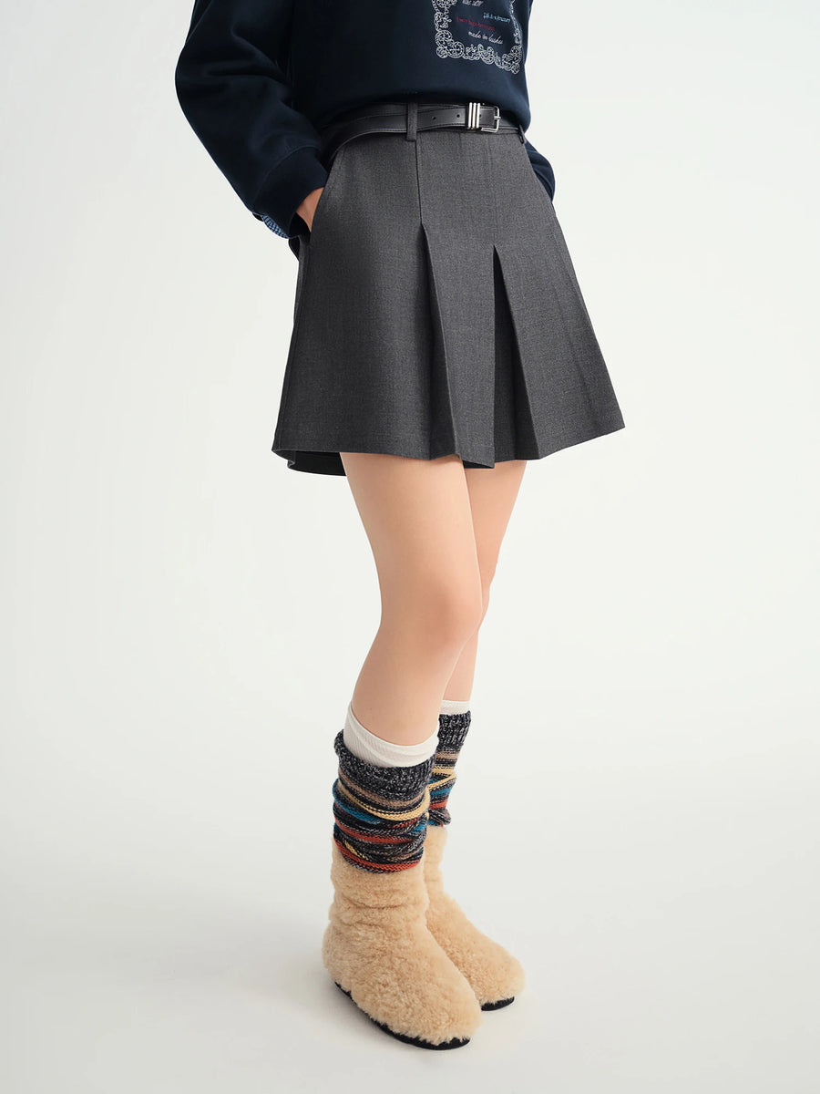 Person wearing a dark gray pleated skirt with colorful socks on a white background