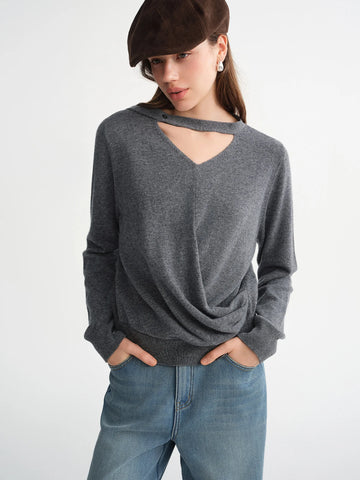 Woman wearing a gray sweater with cut-out design and blue jeans on a white background