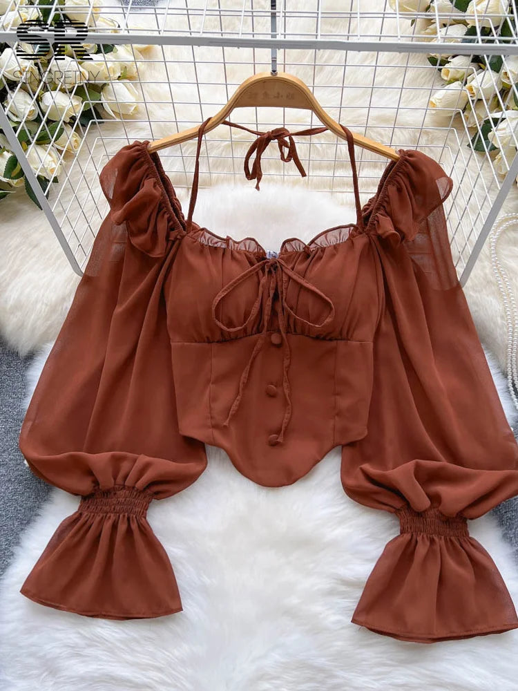 Brown blouse with ruffled sleeves on a hanger against a white background