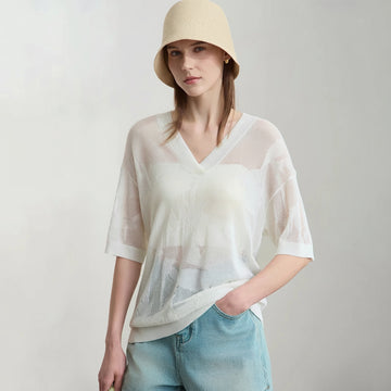 Woman wearing a white mesh top and beige hat with 'Amii' branding.